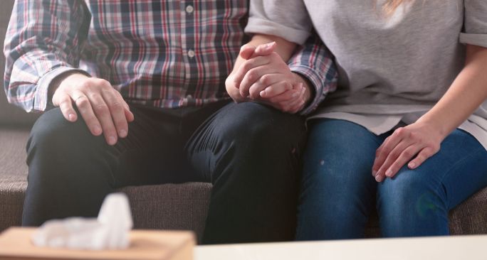 医師が患者の手を優しく握って励ましている